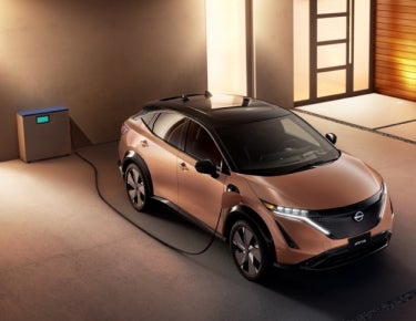 Nissan ARIYA plugged-in and charging outside a home | Ed Martin Nissan in Indianapolis IN