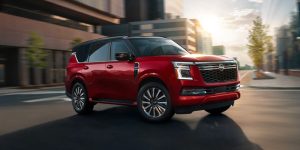 2025 Kia Telluride driving through a modern city street, showcasing its bold front design and premium SUV styling.