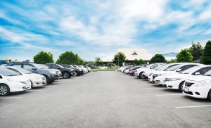 A row of parked cars in a dealership lot with a clear sky in the background.