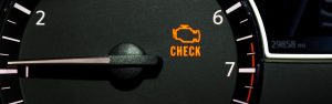 A close-up of a car dashboard showing the "Check Engine" light illuminated.
