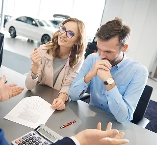 Couple reviewing paperwork with a finance manager at a desk