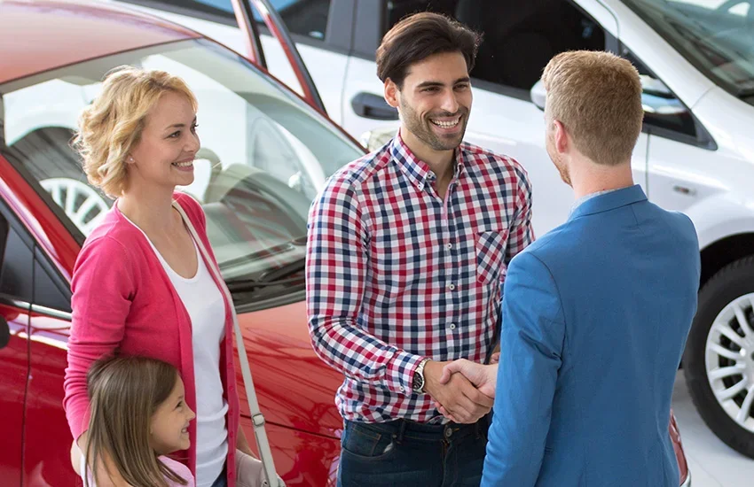 Ed Martin Nissan salesperson shaking hands with a customer while his family looks on