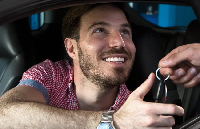 Smiling driver reaching out from a car to take the keys