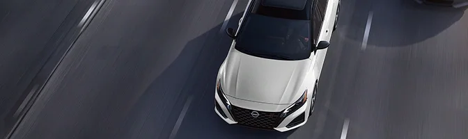 White Nissan Altima driving on a road