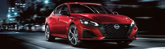 Red Nissan Altima driving along a city street
