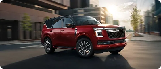 Red Nissan Armada driving on a city street, front three-quarter view