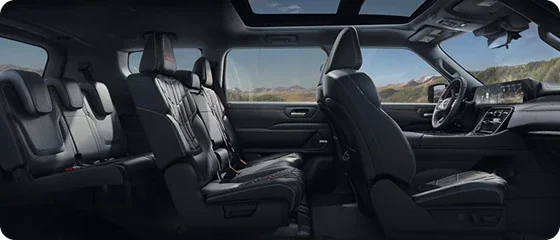 Interior of the 2026 Nissan Armada PRO-4X 4WD showing all three rows of black quilted leather seats and the panoramic roof
