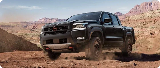 2026 Nissan Frontier PRO-4X 4x4 in black climbing a rocky desert trail, front three-quarter view