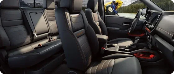 Interior of the 2026 Nissan Frontier PRO-4X 4x4 Crew Cab showing both rows of PRO-4X embroidered seats with orange stitching and the center console