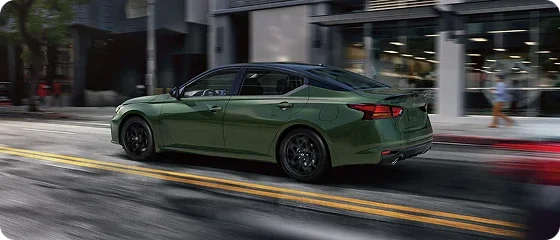 2026 Nissan Altima SV in green driving down a city street, rear three-quarter view