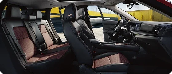 Interior of the 2026 Nissan Kicks SV AWD showing both rows of black and red cloth seats, the steering wheel and the 12.3-inch touchscreen