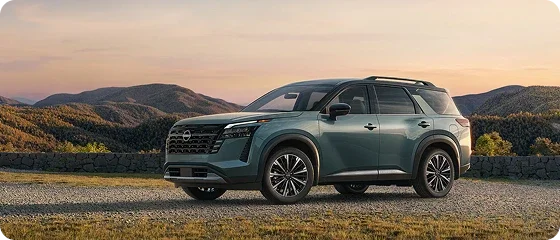 2026 Nissan Pathfinder Platinum 4WD in teal parked on a gravel overlook with rolling hills behind it, side view
