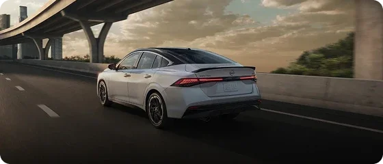 2026 Nissan Sentra SV in white on a highway beneath an overpass at dusk, rear three-quarter view