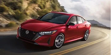 Red Nissan sedan driving along a road