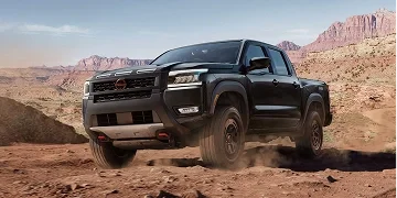 Black Nissan Frontier pickup driving through desert terrain