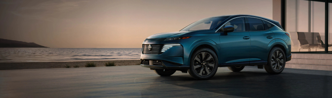 Blue Nissan SUV parked by the water at sunset