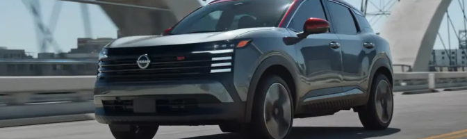Gray Nissan SUV with a red roof driving over a city bridge