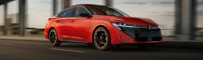 Red Nissan sedan driving across a bridge