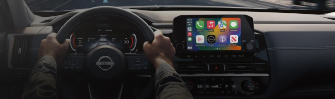 Driver's hands on a Nissan steering wheel beside the center touchscreen