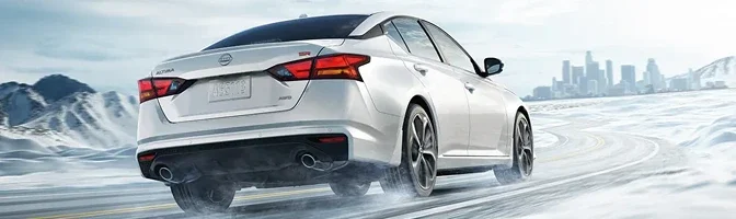 White 2026 Nissan Altima driving away along a snow-covered road