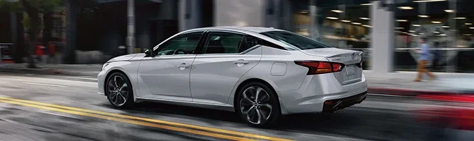 Silver 2026 Nissan Altima driving along a city street, the background blurred with motion