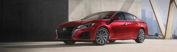 Red 2026 Nissan Altima parked on open pavement beside a concrete wall