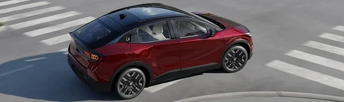 Overhead rear view of a red 2026 Nissan LEAF turning through a city intersection