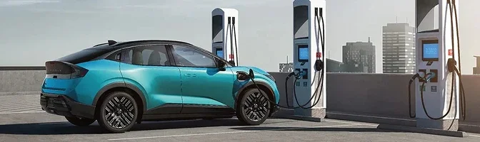 Turquoise 2026 Nissan LEAF plugged in at a row of public fast chargers