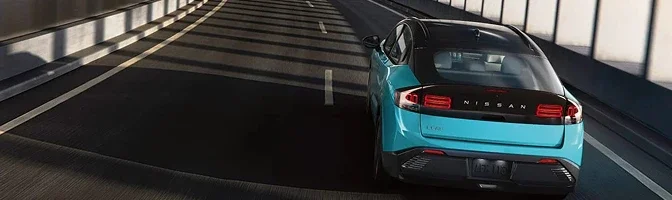 Rear view of a turquoise 2026 Nissan LEAF driving away along a tunnel road