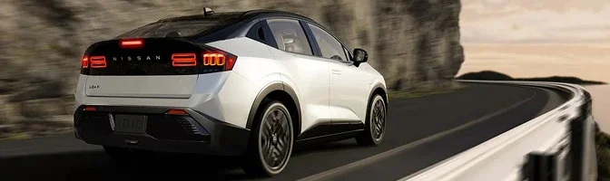 Rear three-quarter view of a white 2026 Nissan LEAF on a winding coastal road