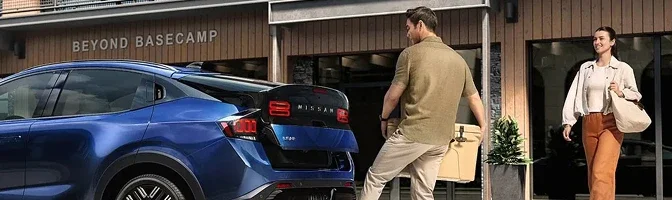 Blue 2026 Nissan LEAF parked outside a building as two people walk toward it