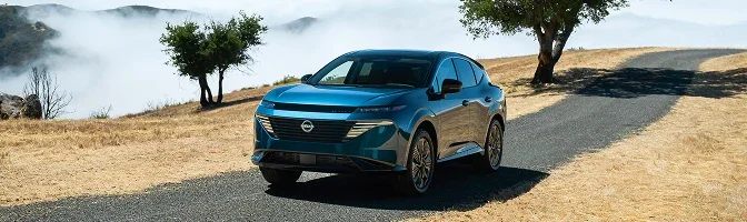 Blue 2026 Nissan Murano parked on a hillside road above low cloud
