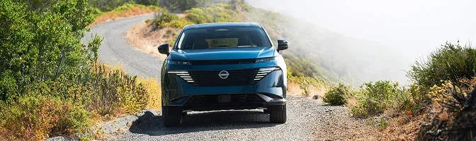 Front view of a blue 2026 Nissan Murano on a gravel road above a fog-filled valley