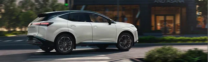 White 2026 Nissan Murano driving past a row of city storefronts