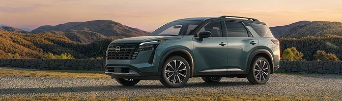 Green 2026 Nissan Pathfinder parked at an overlook above rolling hills at sunset