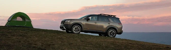2026 Nissan Pathfinder parked beside a tent on a grassy hilltop at dusk