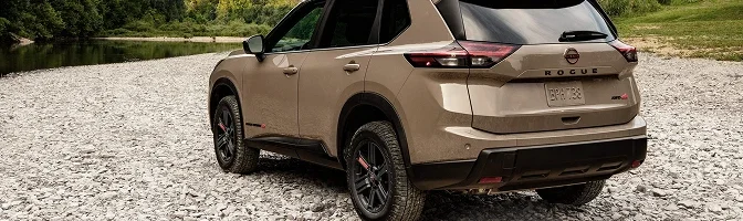 Rear view of a sand-colored Nissan Rogue Rock Creek parked on a gravel bank