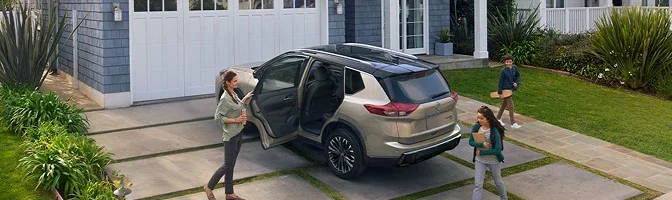 Family loading a silver 2026 Nissan Rogue in a suburban driveway