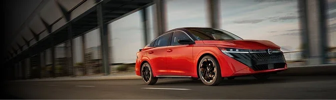 Red 2026 Nissan Sentra driving past a covered walkway